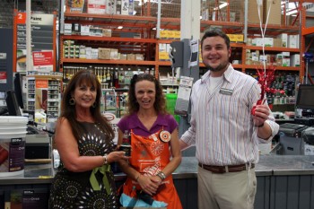 Chris Cannon, director of communications, and Sandra Lindsay, president of the Board of Directors, present a Superstar of Service award to Donna Brumbelow of Home Depot.
